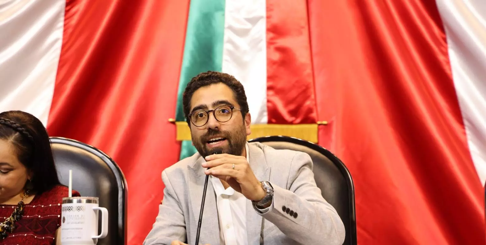 Jose maria behind mic in front of mexican flag
